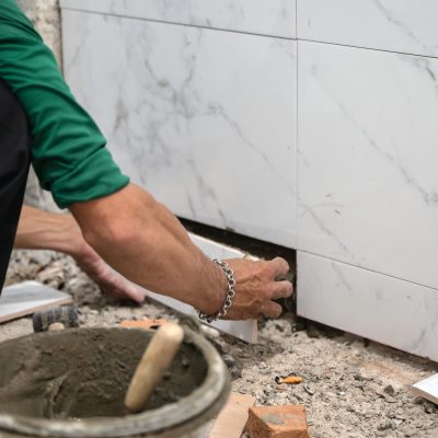 Male tiler using trowel laying marble tile with cement in bathroom. Housing development, Interior improvement renovation